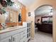 Bathroom with a white vanity, large mirror and the bedroom is seen through an arched opening at 2810 Horton Rd, Kissimmee, FL 34744