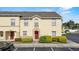 Tan two-story townhouse featuring a red front door, tidy landscaping, and convenient parking at 2867 Club Cortile Cir, Kissimmee, FL 34746