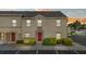 Tan two-story townhouse featuring a red front door, tidy landscaping, and convenient parking at 2867 Club Cortile Cir, Kissimmee, FL 34746