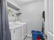 Functional laundry room with washer, dryer, storage shelf, and cleaning supplies at 2867 Club Cortile Cir, Kissimmee, FL 34746