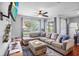 Inviting living area featuring a large gray sectional sofa, mounted TV, and hardwood floors at 2867 Club Cortile Cir, Kissimmee, FL 34746