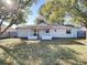 A view of the backyard showing the back of the home with a covered patio area and fence with mature trees at 430 Short Dr, Kissimmee, FL 34759