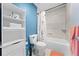 Well-lit bathroom with a tub and shower, storage shelving and blue accent wall at 4551 Hunting Lodge Dr, St Cloud, FL 34772