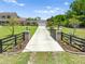Gated entrance opening up to a paved driveway and a charming house beyond manicured lawns at 4551 Hunting Lodge Dr, St Cloud, FL 34772