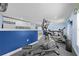 Bright home gym featuring an elliptical machine, treadmill, storage cabinets and blue accent wall at 4551 Hunting Lodge Dr, St Cloud, FL 34772