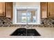 Kitchen sink area features granite counters, mosaic tile backsplash and pass-through to the outdoor area at 4551 Hunting Lodge Dr, St Cloud, FL 34772