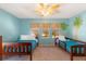 Bright, cheerful bedroom with twin beds, palm tree wall art and a tropical ceiling fan at 477 Orange Cosmos Blvd, Davenport, FL 33837