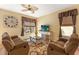 Cozy living room features wood floors, a ceiling fan, comfortable seating, and natural light at 477 Orange Cosmos Blvd, Davenport, FL 33837
