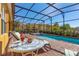 Enjoy the screened-in pool and hot tub from the brick patio with a cocktail table and lounge chairs at 477 Orange Cosmos Blvd, Davenport, FL 33837