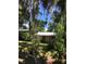 View of the home and the carport with blue metal roof, surrounded by green lawns and various plants at 5019 Pineapple St, Lake Wales, FL 33898