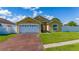 Inviting yellow home with well-manicured lawn, two-car garage, and white fence at 5100 Violet Ln, Kissimmee, FL 34758