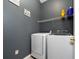 Well-lit laundry room with gray walls, a wire rack shelf, and white washer and dryer at 5100 Violet Ln, Kissimmee, FL 34758