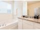 Bright bathroom featuring a tub under a window and granite countertops at 5231 Wildwood Way, Davenport, FL 33837