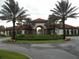 Elegant entrance to the community center, beautifully landscaped with palm trees and colorful flower beds at 5231 Wildwood Way, Davenport, FL 33837