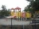 A brightly colored playground, fenced in for safety, featuring slides and climbing structures for enjoyment at 5231 Wildwood Way, Davenport, FL 33837