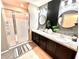 Modern bathroom with double sinks, stylish mirrors, and a walk-in shower with glass doors at 144 Foxtail Loop, Davenport, FL 33837