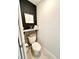 Stylish half bathroom with floating shelf, modern black accent wall and decor, plus wood-look tile flooring at 144 Foxtail Loop, Davenport, FL 33837
