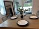 Close-up on a dining table featuring modern place settings, with a mirror and outdoor view in the background at 144 Foxtail Loop, Davenport, FL 33837