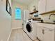 Laundry room featuring a sink, front loading machines, tile flooring, and white cabinets at 20414 Quinn St, Orlando, FL 32833