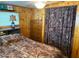 Inviting bedroom featuring wood paneled walls, a queen-sized bed, and camo-themed curtain creates a rustic retreat at 2082 Starboard Dr, Geneva, FL 32732
