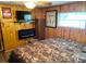 Comfortable bedroom with wood paneled walls, electric fireplace, and a camo-themed bedspread for a rustic feel at 2082 Starboard Dr, Geneva, FL 32732