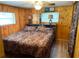 Warm bedroom featuring wood paneled walls, a queen-size bed, and rustic-style lamps for cozy ambiance at 2082 Starboard Dr, Geneva, FL 32732