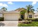 Charming single-story home featuring a two-car garage, manicured lawn, and tropical landscaping at 2263 Mallory Cir, Haines City, FL 33844