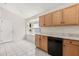 A kitchen with wood cabinets, neutral countertops, white tile floors, and a black dishwasher at 2263 Mallory Cir, Haines City, FL 33844