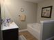 A clean bathroom with a soaking tub, framed picture, and wood look flooring at 2357 Great Harbor Dr, Kissimmee, FL 34746