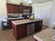 Open kitchen featuring an island, dark wood cabinets, tiled backsplash, and modern appliances at 2357 Great Harbor Dr, Kissimmee, FL 34746