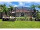 View of screened-in pool area with lush landscaping, a variety of plants, and palm trees at 2357 Great Harbor Dr, Kissimmee, FL 34746