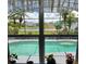 Relaxing screened-in pool view through the window overlooking the lake and manicured landscaping at 2357 Great Harbor Dr, Kissimmee, FL 34746