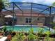 In-ground pool surrounded by landscaping including potted plants and colorful flowers with a screened enclosure at 2357 Great Harbor Dr, Kissimmee, FL 34746