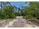 Gravel driveway leading through wooden gates and lush greenery, creating a grand entrance to a private property at 2576 R E Byrd Rd, Frostproof, FL 33843