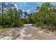 View of the property entrance with gravel road, wooden gate and lush surrounding trees at 2576 R E Byrd Rd, Frostproof, FL 33843