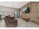 Comfortable living room area with decorative stone wall, reclining sofa, and wood-look tile floors at 2576 R E Byrd Rd, Frostproof, FL 33843