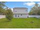 View of a home's backyard featuring a fenced yard with green grass and a young tree at 303 Anchovie Ct, Poinciana, FL 34759