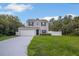 Two-story home featuring gray siding, black shutters, a well-manicured lawn, and an attached garage at 303 Anchovie Ct, Poinciana, FL 34759