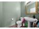 Charming half-bathroom with an elegant gold-framed mirror and a pedestal sink, complemented by muted green walls at 3144 Dark Sky Dr, Harmony, FL 34773
