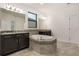 Bright bathroom features double sinks, a soaking tub, tiled floors and dark wood cabinets at 3212 Preserve Dr, Orlando, FL 32824