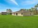 Expansive backyard with lush green lawn and a view of the rear exterior of the house at 35 Peterlee Ct, Kissimmee, FL 34758