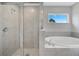 Modern bathroom featuring a glass shower enclosure, a soaking tub, and a window with outdoor view at 35 Peterlee Ct, Kissimmee, FL 34758