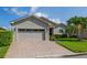 Well-maintained single-story home with brick driveway, two-car garage, and lush green lawn at 4056 Ashton Club Dr, Lake Wales, FL 33859