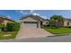 Single-story home with brick driveway, two-car garage, and beautifully landscaped front yard with palm trees at 4056 Ashton Club Dr, Lake Wales, FL 33859