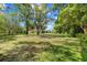 Spacious green backyard featuring trees, a pool, and a fenced perimeter, perfect for outdoor enjoyment at 6441 Nightwind Cir, Orlando, FL 32818