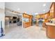 Open kitchen with stainless appliances, wood cabinets, tile floors, and view of brick fireplace at 6441 Nightwind Cir, Orlando, FL 32818