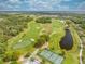 Aerial view of a golf course community with tennis courts and a pond next to lush green fairways and greens at 7413 Bent Tree Loop, St Cloud, FL 34771