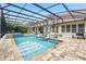 Inviting screened-in pool area with a hot tub, basketball hoop, and outdoor kitchen, perfect for relaxation and entertaining at 8214 Lake Serene Dr, Orlando, FL 32836