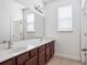 Bathroom with double sinks, large mirror, and cherry wood cabinets at 8359 Lookout Pointe Dr, Windermere, FL 34786