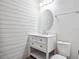 Elegant powder room featuring a white vanity, an oval mirror, and shiplap walls, offering a fresh and stylish space at 8359 Lookout Pointe Dr, Windermere, FL 34786